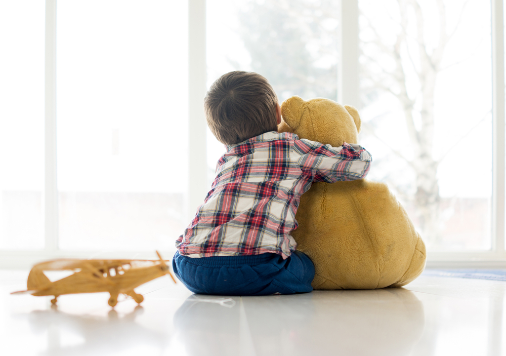 Little child sitting in living room with teddy bear